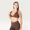 Modella indossa il top sportivo marrone Bombafit Sense con effetto push-up e logo BMBFT sulla fascia sottoseno