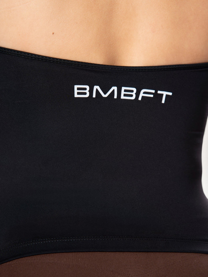Dettaglio del top sportivo nero Bombafit con logo bianco stampato sul retro, realizzato in tessuto tecnico elastico.