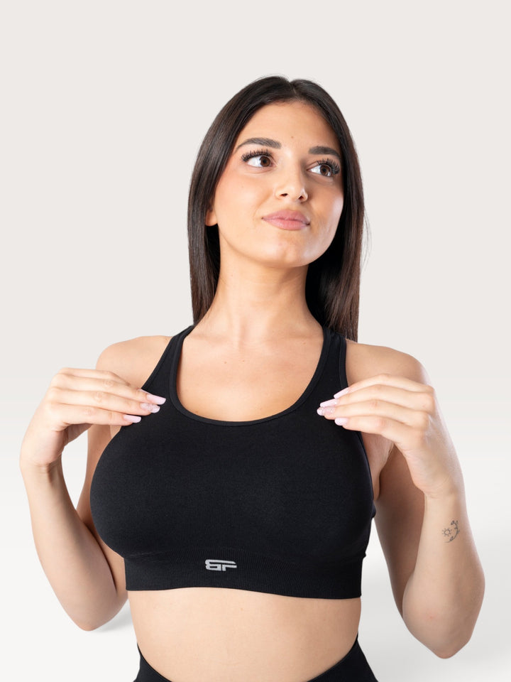 Modella indossa il top sportivo nero Bombafit Active Seamless con design a vogatore e tessuto tecnico traspirante