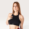 Modella indossa il top sportivo nero Bombafit Go Seamless con design a vogatore e fascia elastica di supporto