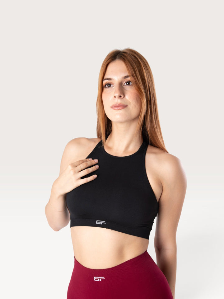 Modella indossa il top sportivo nero Bombafit Go Seamless con design a vogatore e fascia elastica di supporto