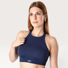 Modella indossa il top sportivo Bombafit Go Seamless blu notte con design a vogatore e logo riflettente