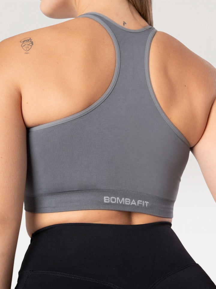 Vista posteriore del top sportivo Bombafit Go Seamless color grafite con design a vogatore e logo sul bordo