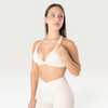 Modella indossa il top sportivo Bombafit Sense beige con spalline incrociate, effetto push-up e logo sottoseno