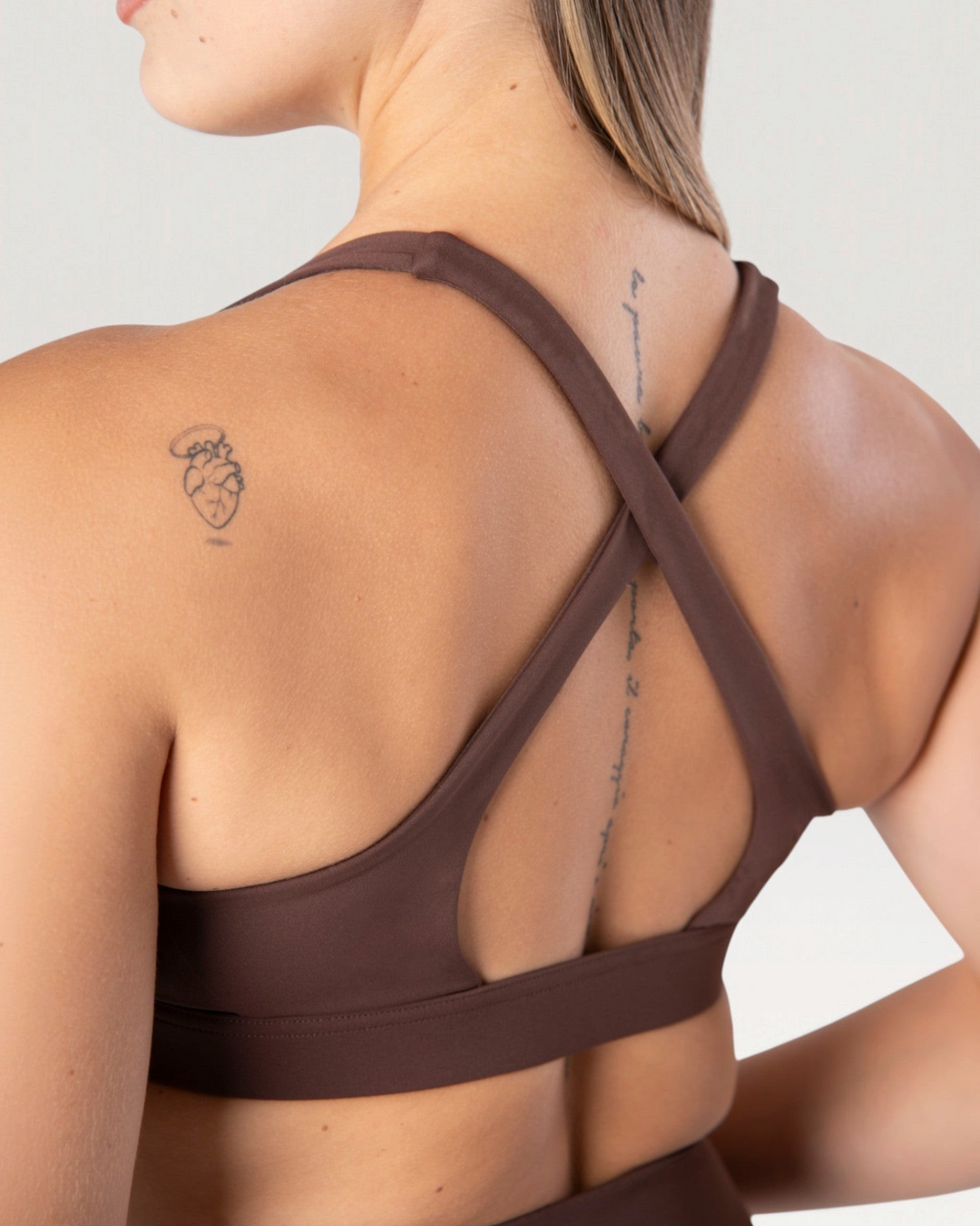 Vista posteriore del top sportivo Bombafit Sense marrone con spalline incrociate e tessuto elasticizzato