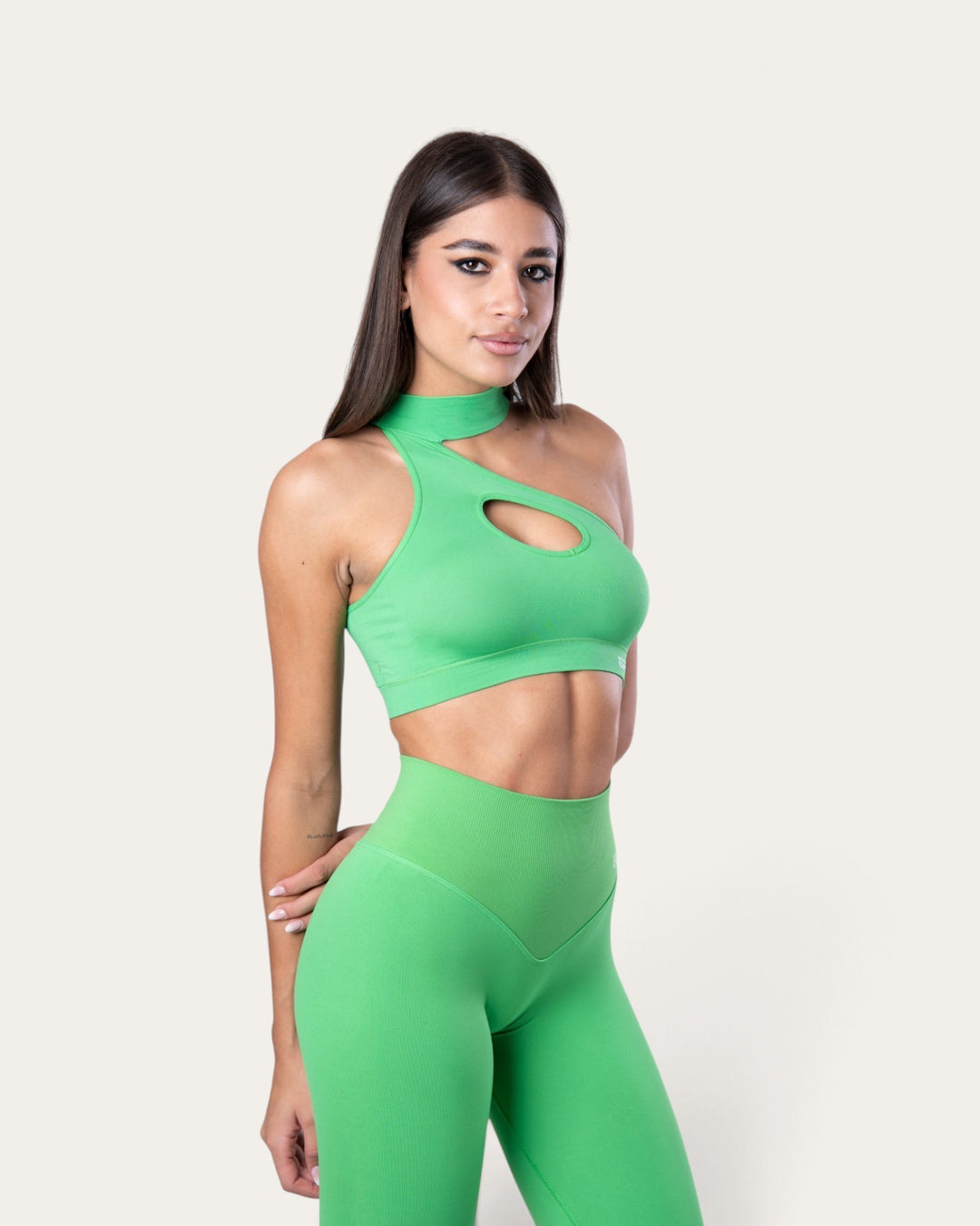 Modella indossa il top sportivo Bombafit Choker Seamless color verde slime con scollo asimmetrico e dettaglio cut-out