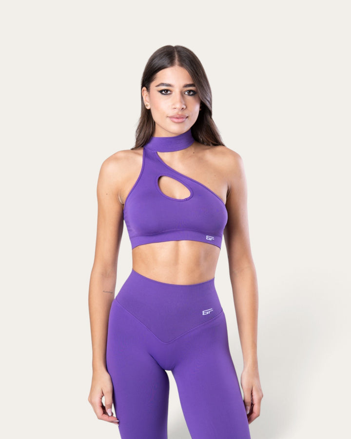Modella indossa il top sportivo viola Bombafit Choker Seamless con design monospalla e dettaglio cut-out