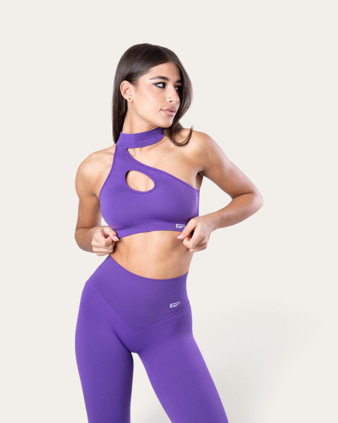 Modella indossa il top sportivo Bombafit Choker Seamless viola con design monospalla e dettaglio cut-out