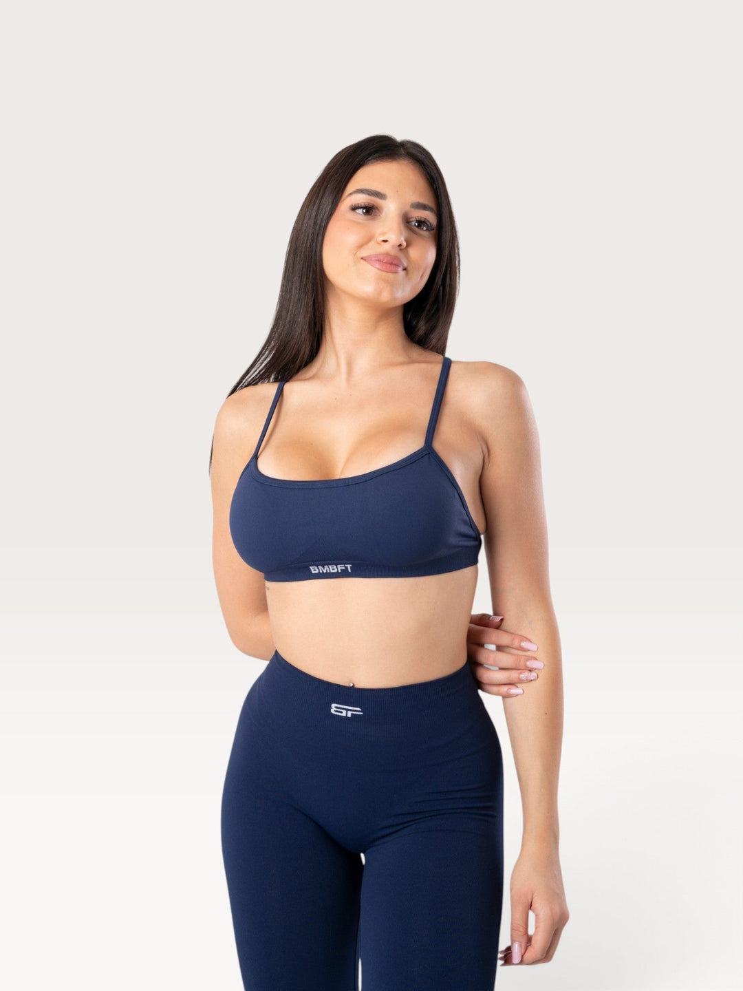 Modella indossa il top sportivo Bombafit Unity blu notte con spalline sottili e tessuto seamless traspirante