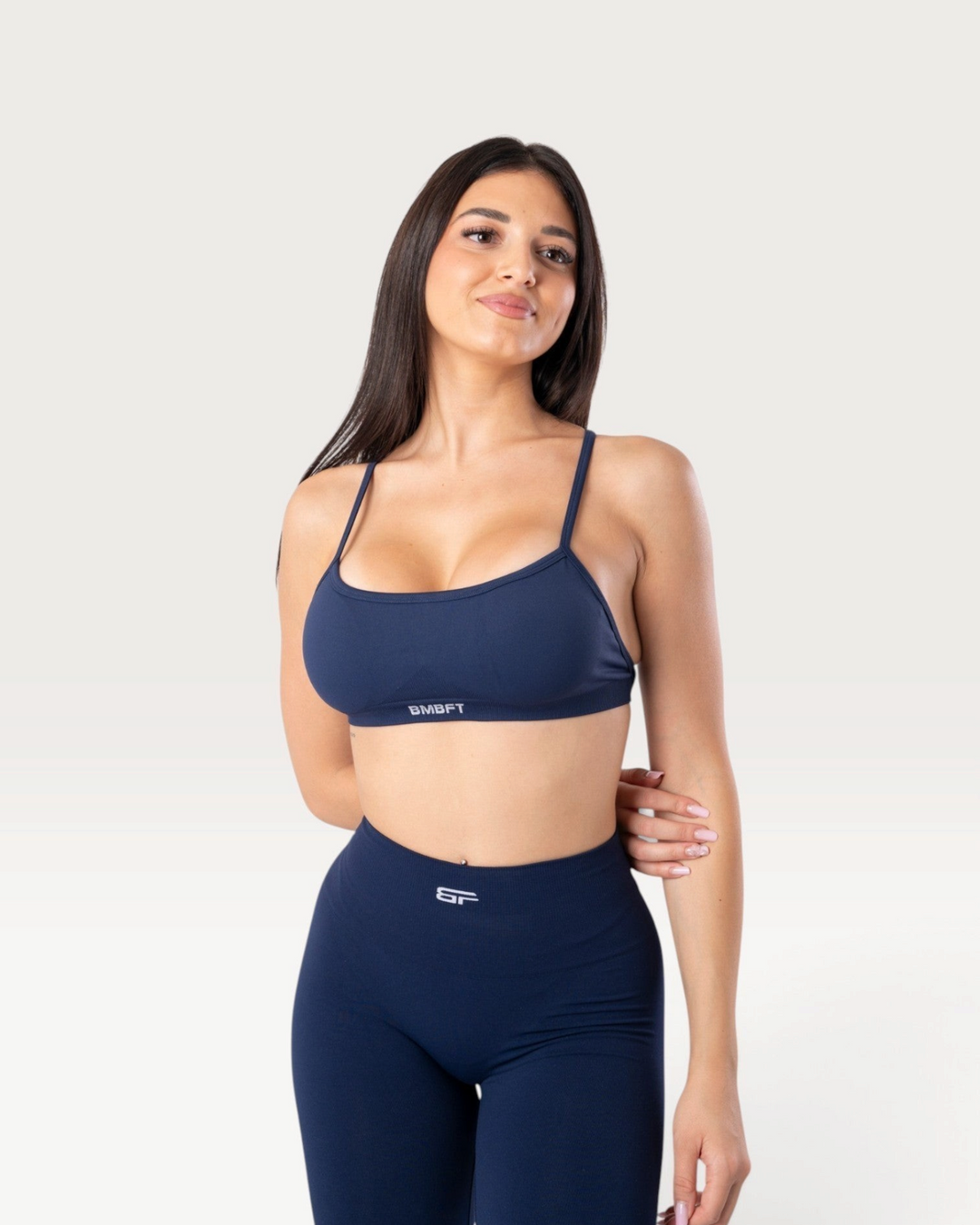 Modella indossa il top sportivo Bombafit Unity blu notte con spalline sottili e tessuto seamless traspirante