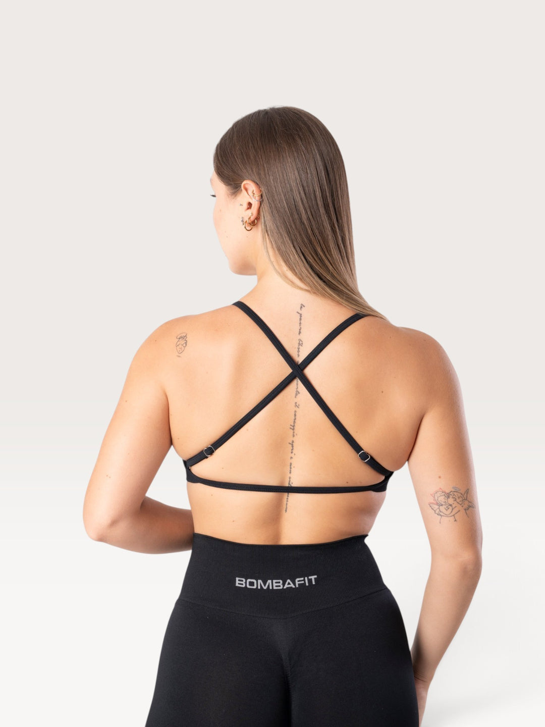 Vista posteriore del top sportivo Bombafit Unity nero con spalline incrociate regolabili e tessuto seamless traspirante
