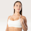 Modella indossa il top sportivo bianco Bombafit Seamless con spalline sottili e banda elastica sotto il seno