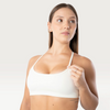 Modella indossa il top sportivo bianco Bombafit Seamless con spalline sottili e banda elastica sotto il seno