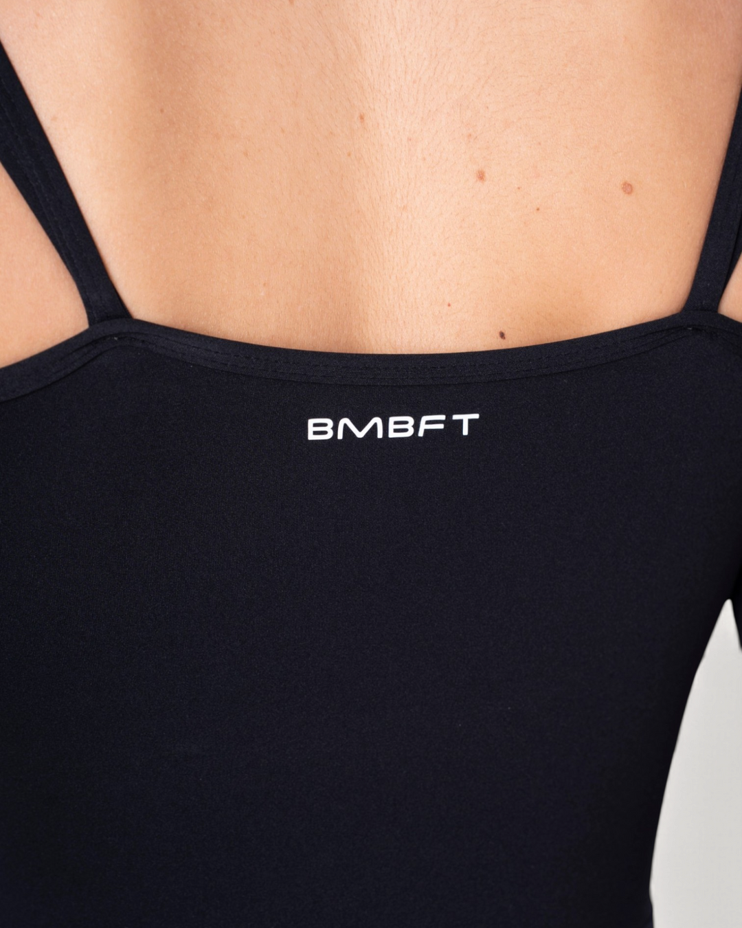 Dettaglio della schiena della tuta intera Diva Jumpsuit nera di Bombafit con logo BMBFT stampato
