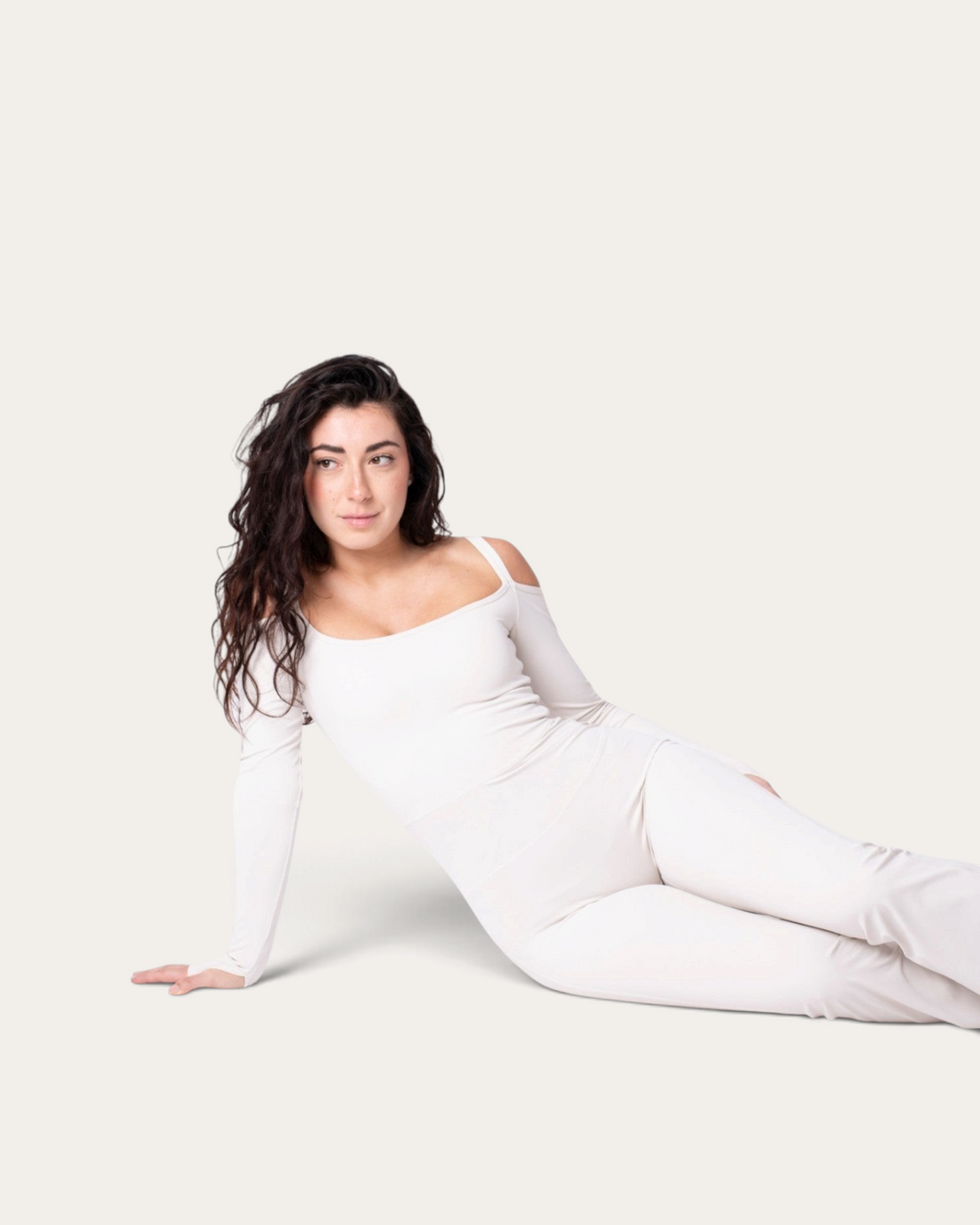 Modella indossa la tuta intera bianca Diva Jumpsuit di Bombafit con maniche lunghe e spalle scoperte
