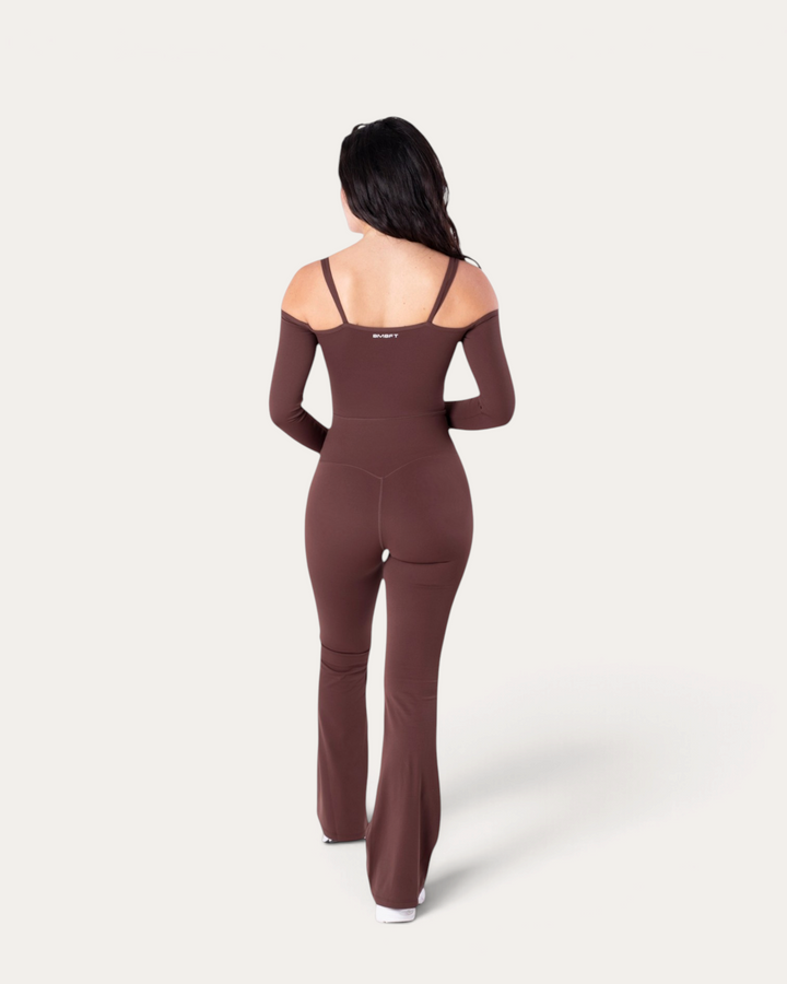 Modella di spalle indossa la tuta intera Diva Jumpsuit marrone di Bombafit con maniche lunghe e spalle scoperte