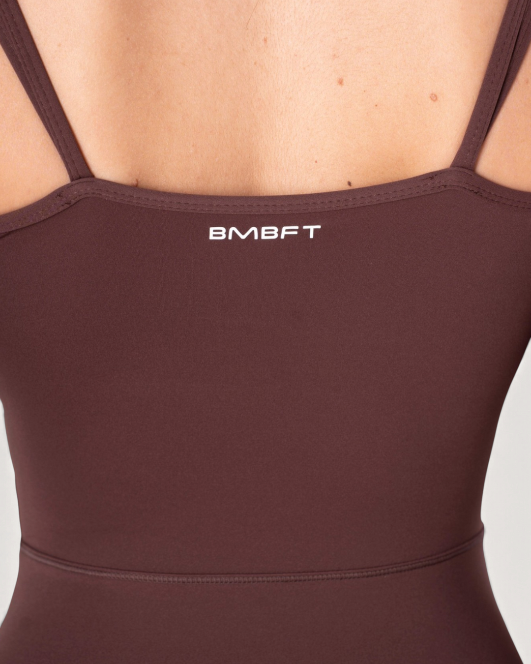 Dettaglio posteriore della tuta intera Diva Bombafit color marrone con spalline sottili e logo BMBFT